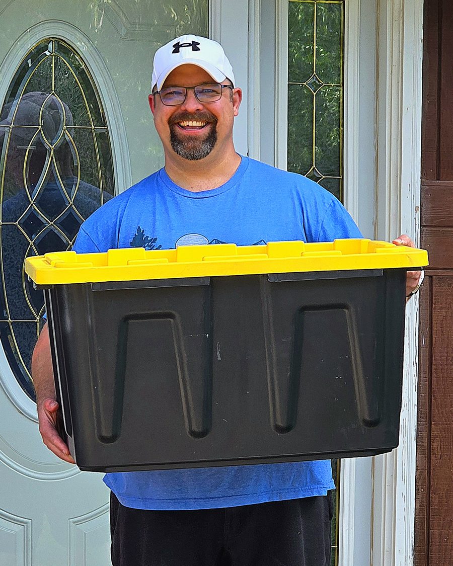 Tori of TNT Rental holding a black and yellow moving tote at the front door in Dickinson